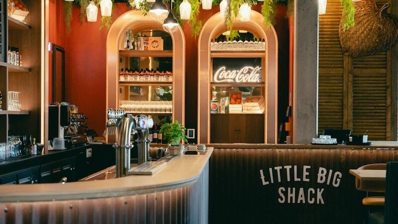 Le bar du Little Big Shack, son nom peint sur le comptoir et ses arches en bois clair.